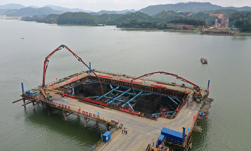 3月21日，在广西上林至横州高速公路建设施工现场，工人们加班加点完成控制性工程——西津郁江特大桥水中承台的浇筑作业。图为在广西上林至横州高速公路西津郁江特大桥建设现场，中铁四局工人在进行水中承台的浇筑施工作业（无人机照片）。（新华社记者 陆波岸 摄）
