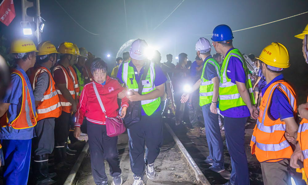 8月2日19时，中铁十四局京唐项目、北京地铁17号线项目80余名工作人员兵分两路，一部分工作人员搬运枕木，重修铁路路基；另一部分工作人员背靠坍塌部分路基，形成爱心人墙，协助被困Z180列车503名乘客解除困境。侯慧 摄